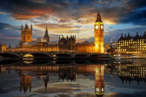 London 2025 travel guide: Westminster and Big Ben illuminated at dusk, reflecting in the Thames, showcasing London's historic and modern fusion.