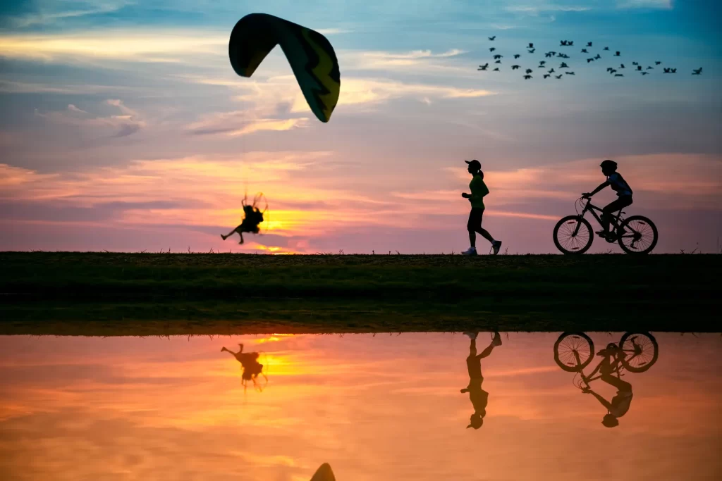 People enjoying outdoor activities at sunset – cycling, running, and paragliding – part of GetYourGuide experiences with Urbe Travel