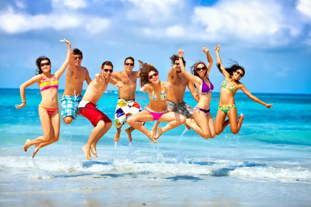 Group of friends jumping on the beach during a boat party in Ibiza