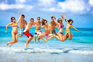 Group of friends jumping on the beach during a boat party in Ibiza