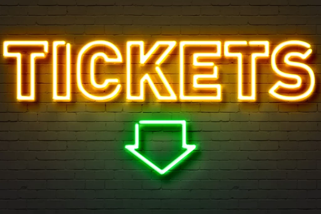 Neon sign showing the word “Tickets” and a green arrow, representing Ibiza party tickets 2025