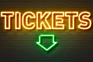 Neon sign showing the word “Tickets” and a green arrow, representing Ibiza party tickets 2025