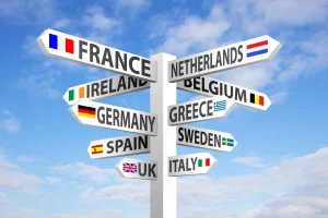 Signpost showing popular Europe Summer 2025 travel destinations including France, Spain, Italy, Greece, UK, Germany, and more under a blue sky.