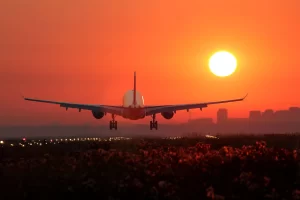 Airplane taking off at sunset on a brightly lit runway, symbolizing international travel and new adventures in 2026